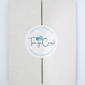 White cardboard box sealed with a sticker with the Tanya Creed Designs logo